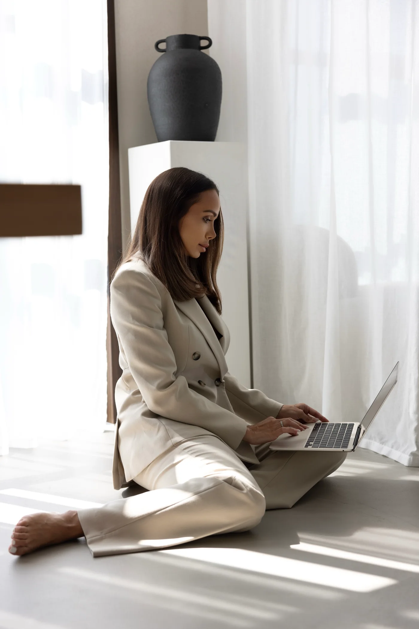 Noemi im beigen Anzug bei der Arbeit am Laptop